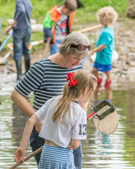 children and adults looking at nets river dipping