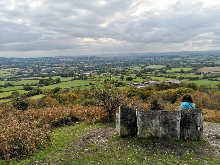 Someone sitting on a bench admiring a view across the landscape