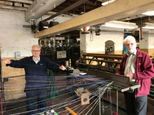two men stood beside a weaving machine