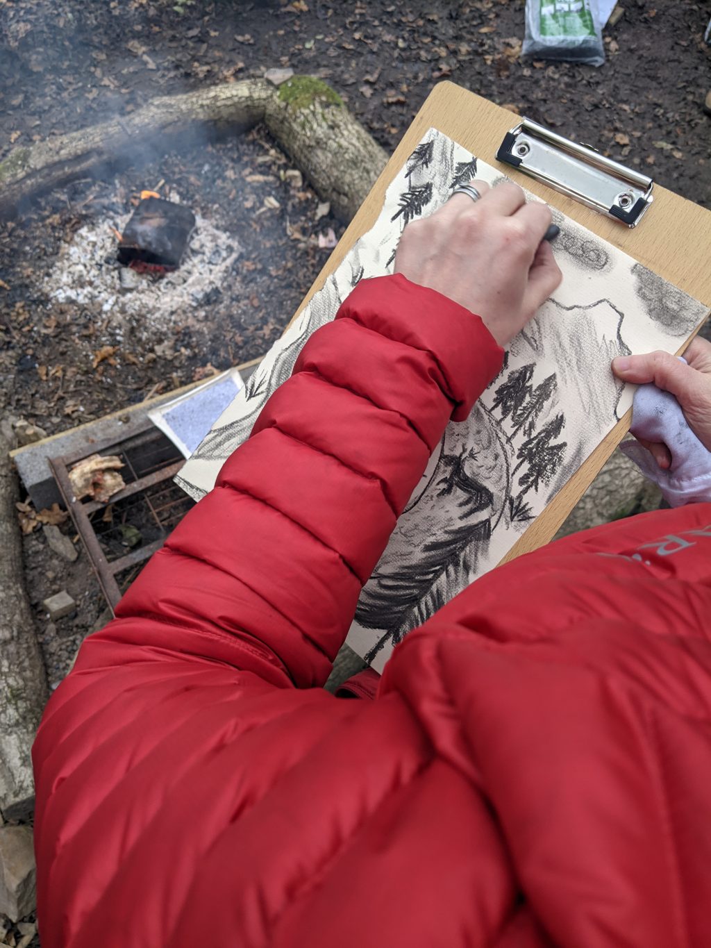 someone wearing a red coat using charcoal creating artwork