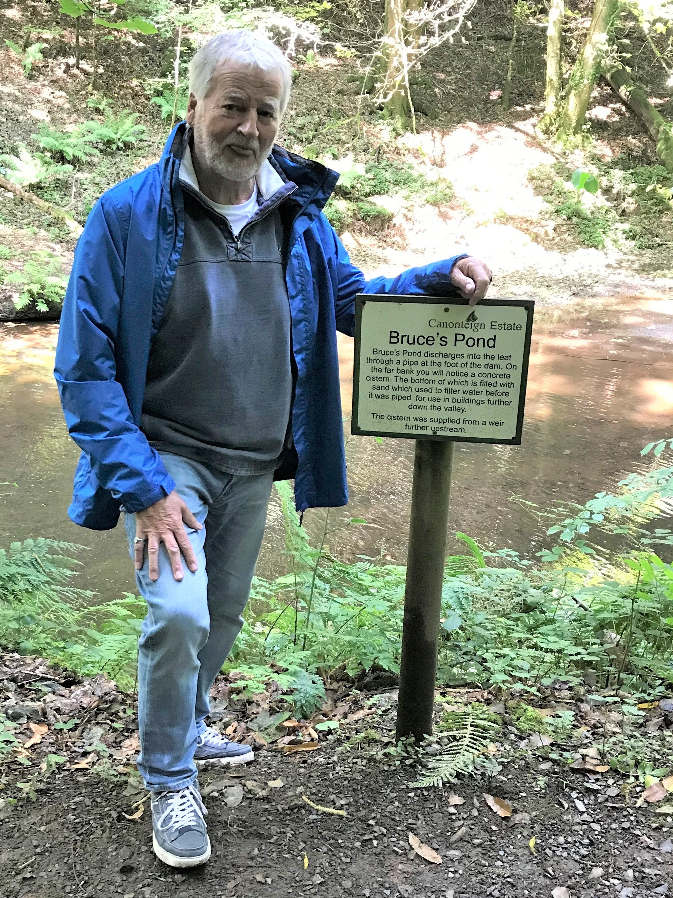 Bruce Payne, Blackdown Hills AONB Chair, standing next to a sign which reads Bruce's pond